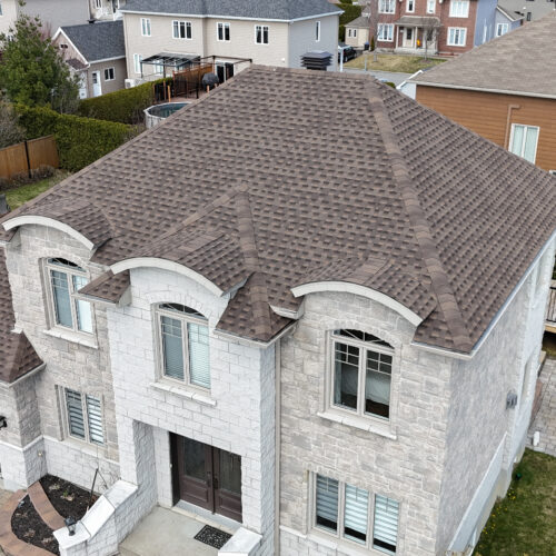 Vue aérienne d'une maison résidentielle avec une nouvelle toiture réalisée par Zoom Toiture, utilisant des matériaux GAF. Grande maison, beige, brique, classique, Québec