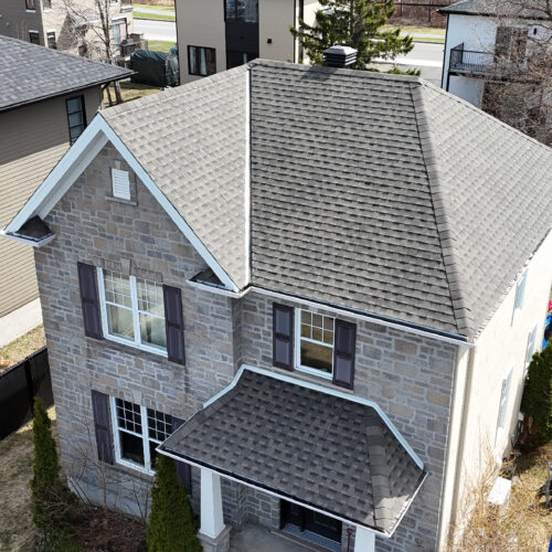 Vue aérienne d'une maison résidentielle avec une nouvelle toiture réalisée par Zoom Toiture, utilisant des matériaux GAF. Maison grise, briques, beige