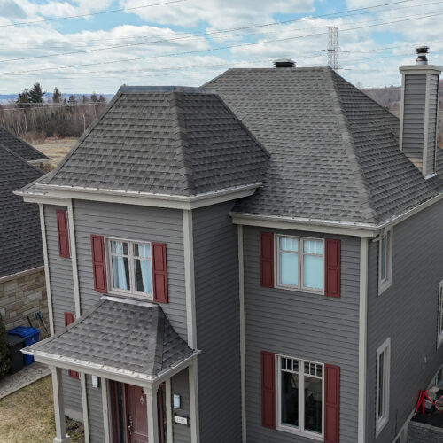 Vue aérienne d'une maison résidentielle avec une nouvelle toiture réalisée par Zoom Toiture, utilisant des matériaux GAF. Maison beige, grise, rouge