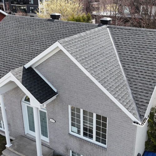 Vue aérienne d'une maison résidentielle avec une nouvelle toiture réalisée par Zoom Toiture, utilisant des matériaux GAF. Maison grise