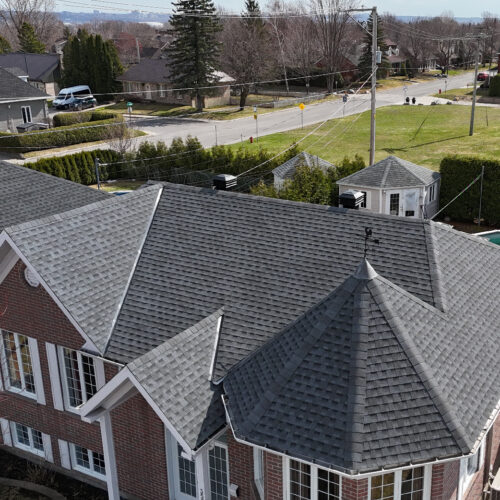 Vue aérienne d'une maison résidentielle avec une nouvelle toiture réalisée par Zoom Toiture, utilisant des matériaux GAF. Maison résidentiel, brique en rouge, toit gris, pignon, Québec, Canada