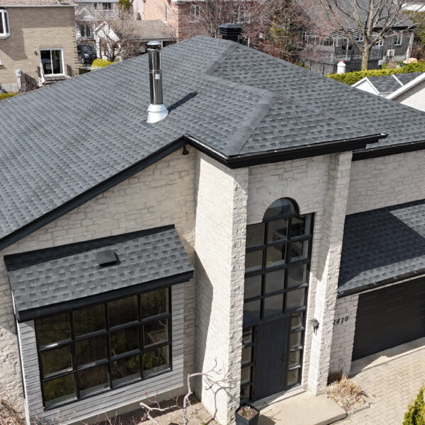 Vue aérienne d'une maison résidentielle avec une nouvelle toiture réalisée par Zoom Toiture, utilisant des matériaux GAF. Grande maison, beige et noir, luxe, Québec, Canada