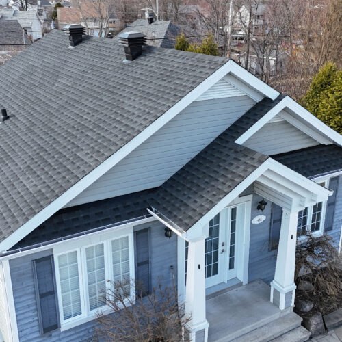 Vue aérienne d'une maison résidentielle avec une nouvelle toiture réalisée par Zoom Toiture, utilisant des matériaux GAF. Petite maison résidentiel, bleu, gris, blanc