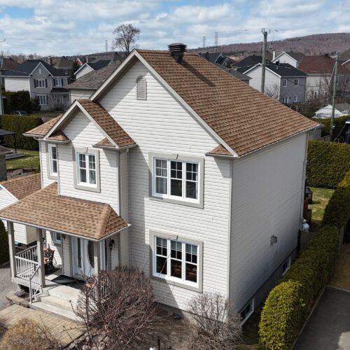 Vue aérienne d'une réalisation résidentielle par Zoom Toiture avec une nouvelle toiture installée sur une maison à revêtement blanc.